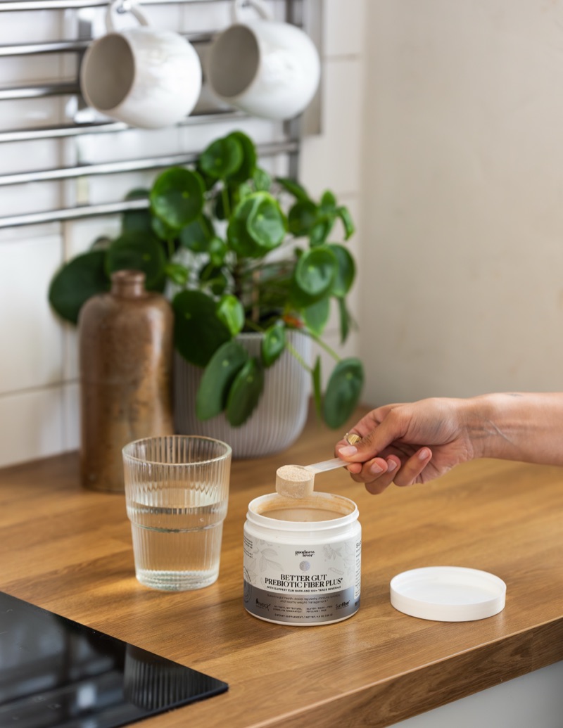 Scooping Better Gut Prebiotic Fiber Plus into a glass of water